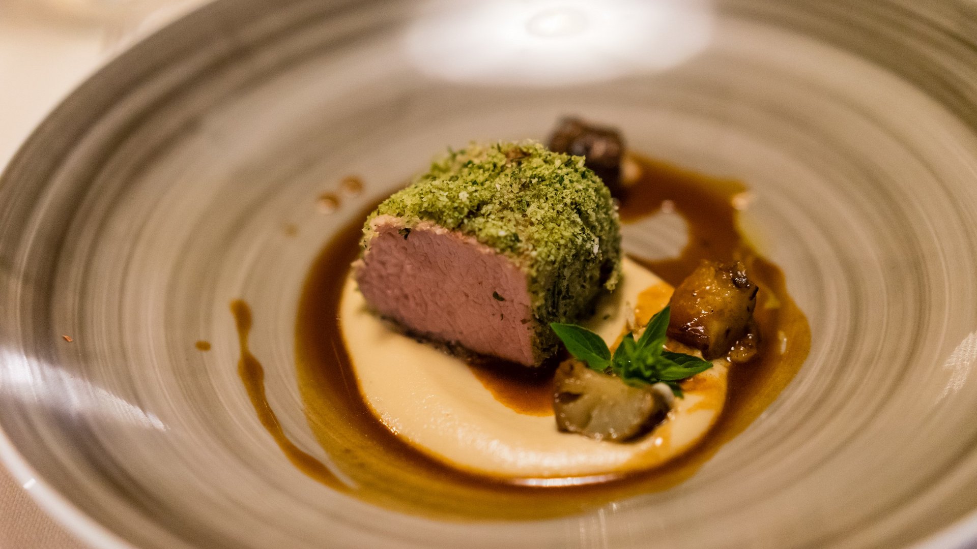 Gourmet haven Erlebnisort Gassenhof Gourmet dish with herb crust, creamy sauce, and vegetables on plate