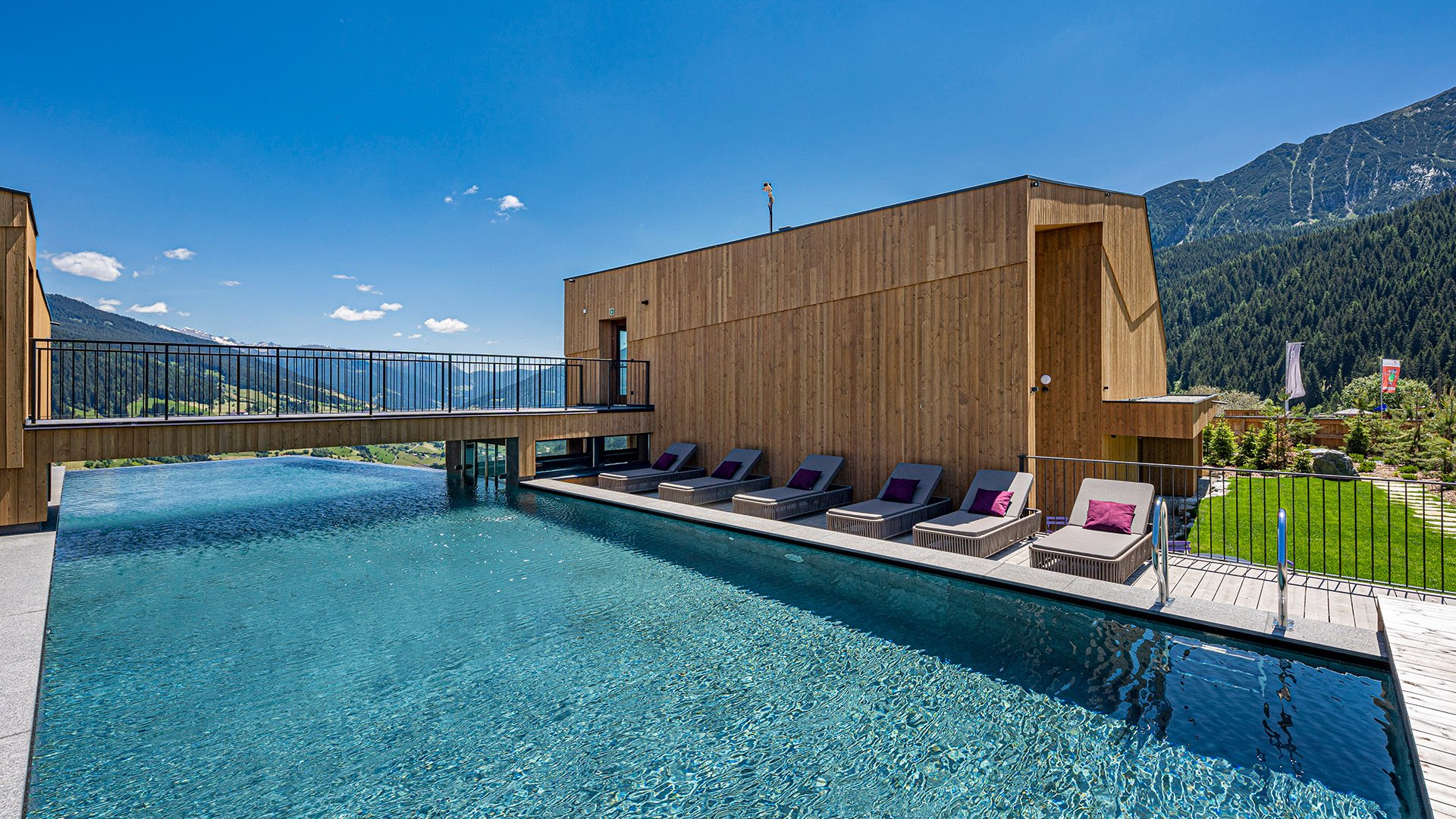 Home Erlebnisort Gassenhof Moderner Holzbau mit Infinity-Pool und Bergblick unter blauem Himmel