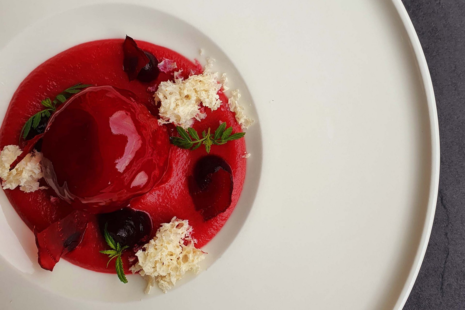 Home Erlebnisort Gassenhof Feines rotes Dessert mit Dekoration auf weißem Teller