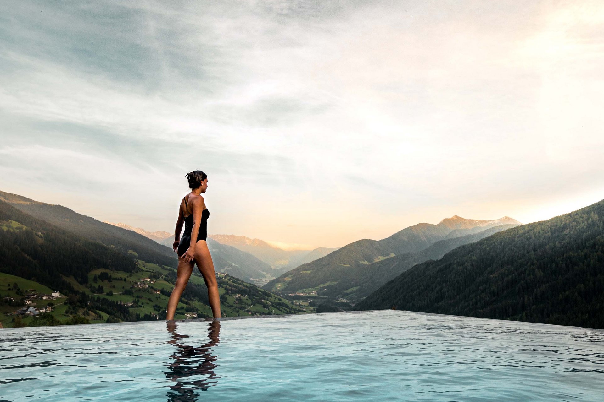 Home Erlebnisort Gassenhof Frau im Badeanzug am Rand eines Infinity-Pools mit Berglandschaft