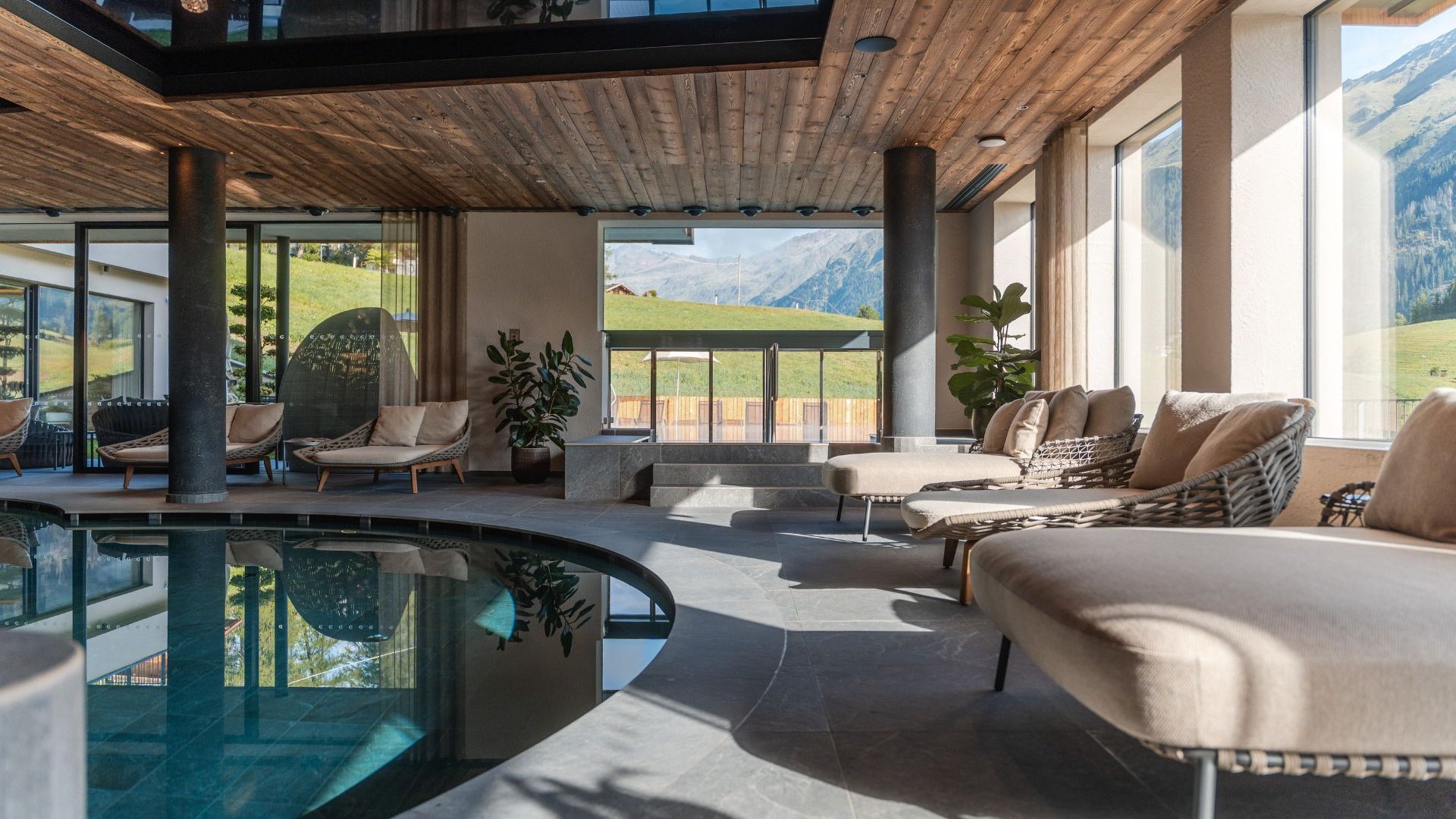 Home Erlebnisort Gassenhof Heller Innenpool mit Liegen und Bergblick durch große Fenster