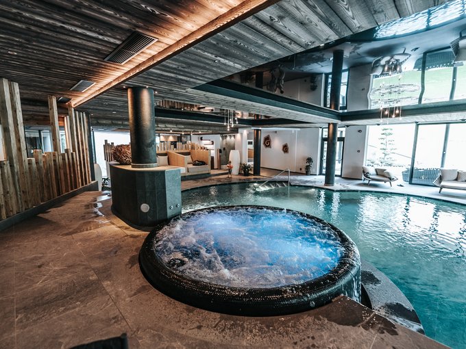 Home Erlebnisort Gassenhof Innenpool mit Whirlpool und moderner Holzdecke in einem Wellnessbereich