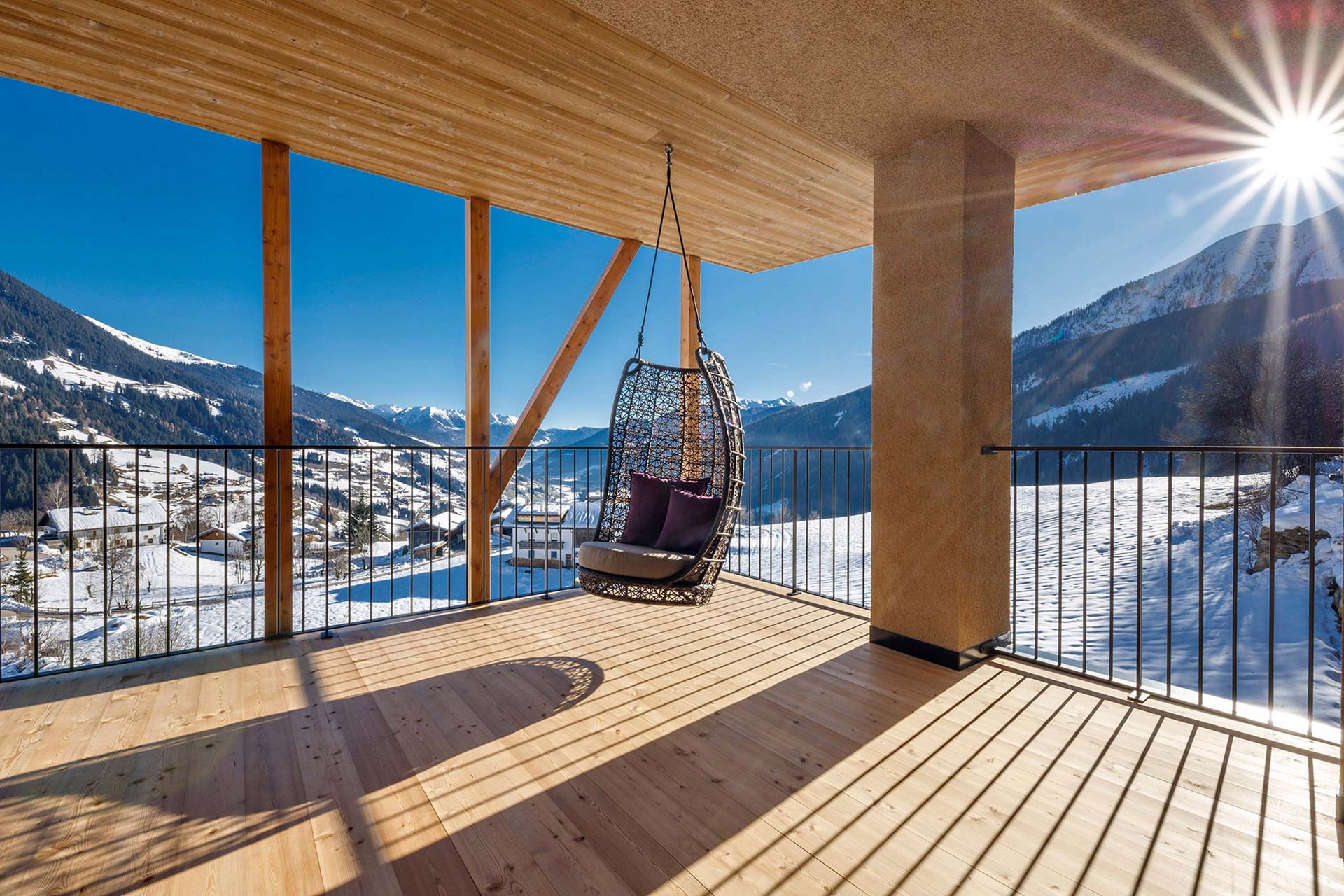 Home Erlebnisort Gassenhof Hängesessel auf Balkon mit Blick auf schneebedeckte Berge und sonnigen Himmel