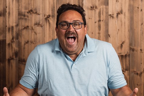 The Volgger family Man with glasses looking surprised and excited in front of wooden wall
