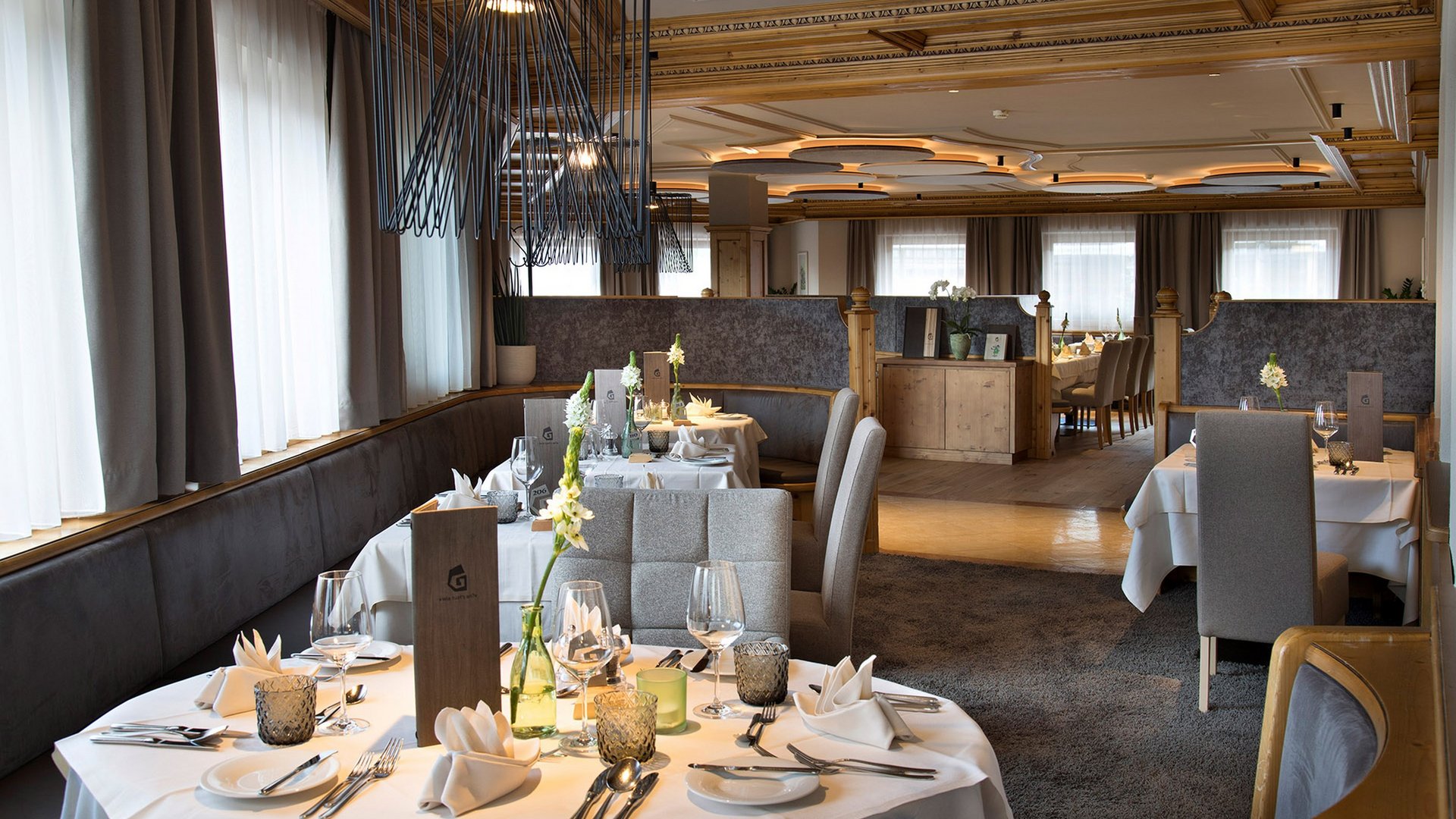 Home Erlebnisort Gassenhof Elegantes Restaurant mit gedeckten Tischen und modernem Holzdekor