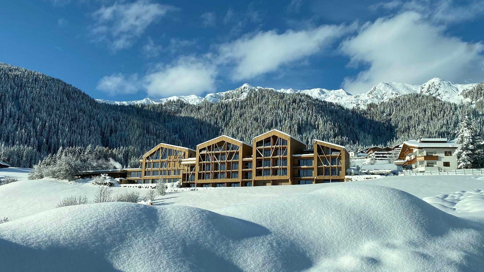 Home Erlebnisort Gassenhof Winterlandschaft mit schneebedeckten Bergen und modernen Holzhäusern