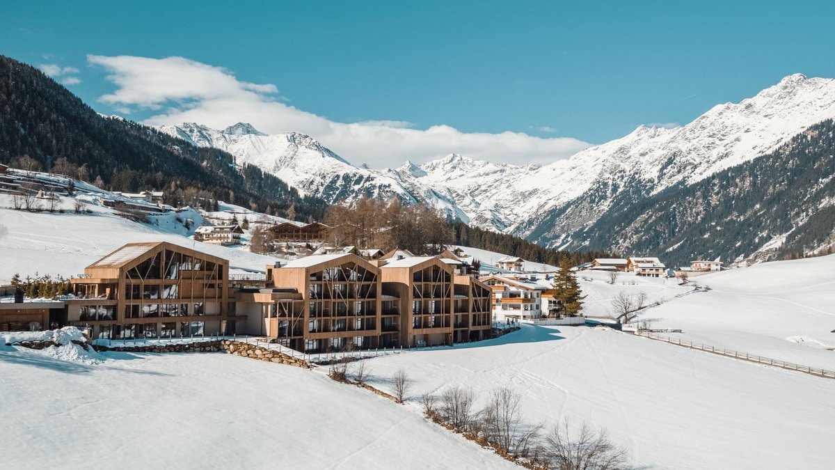 Home Erlebnisort Gassenhof Holzgebäude in verschneitem Tal mit Bergen im Hintergrund