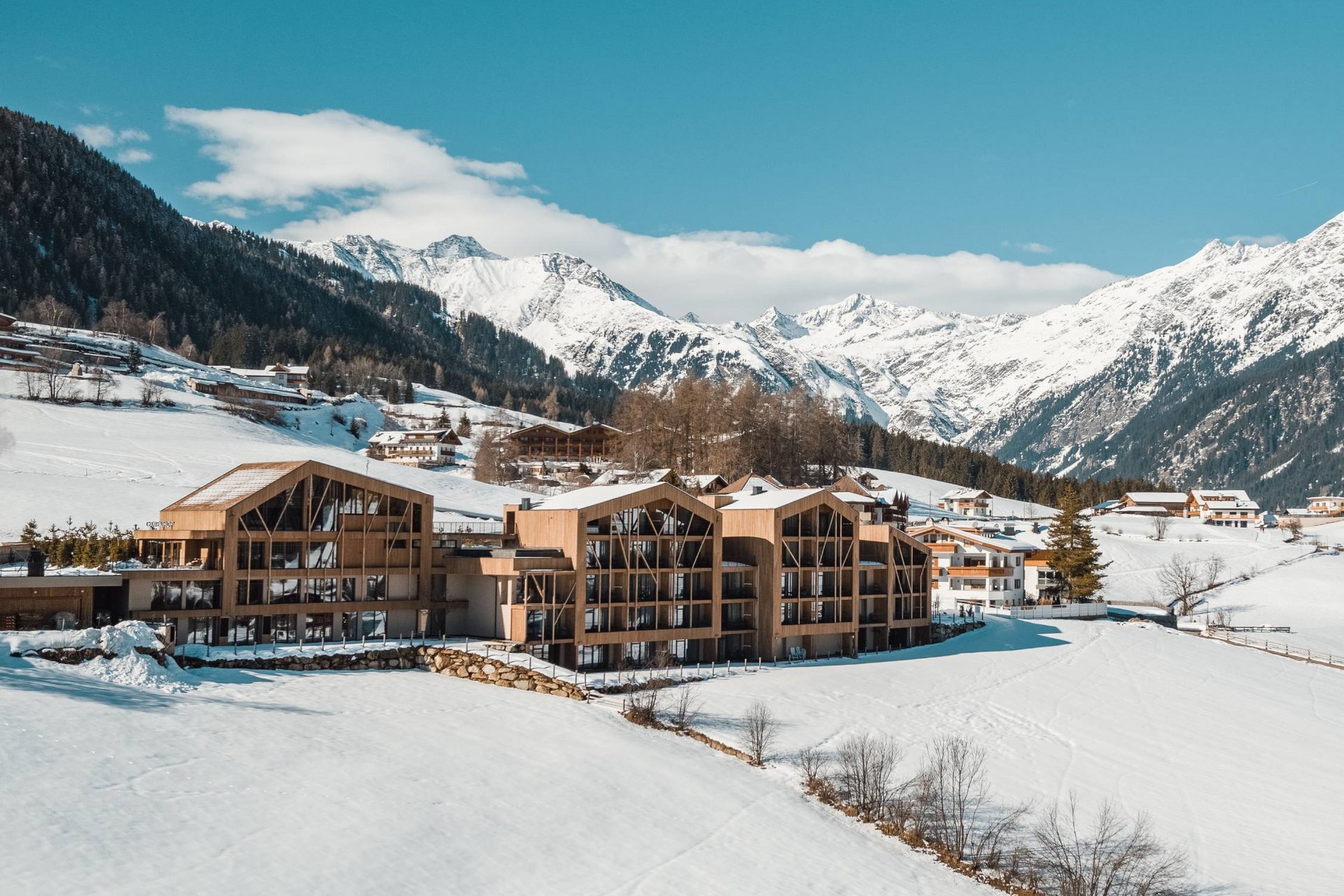 Home Erlebnisort Gassenhof Holzgebäude in verschneitem Tal mit Bergen im Hintergrund