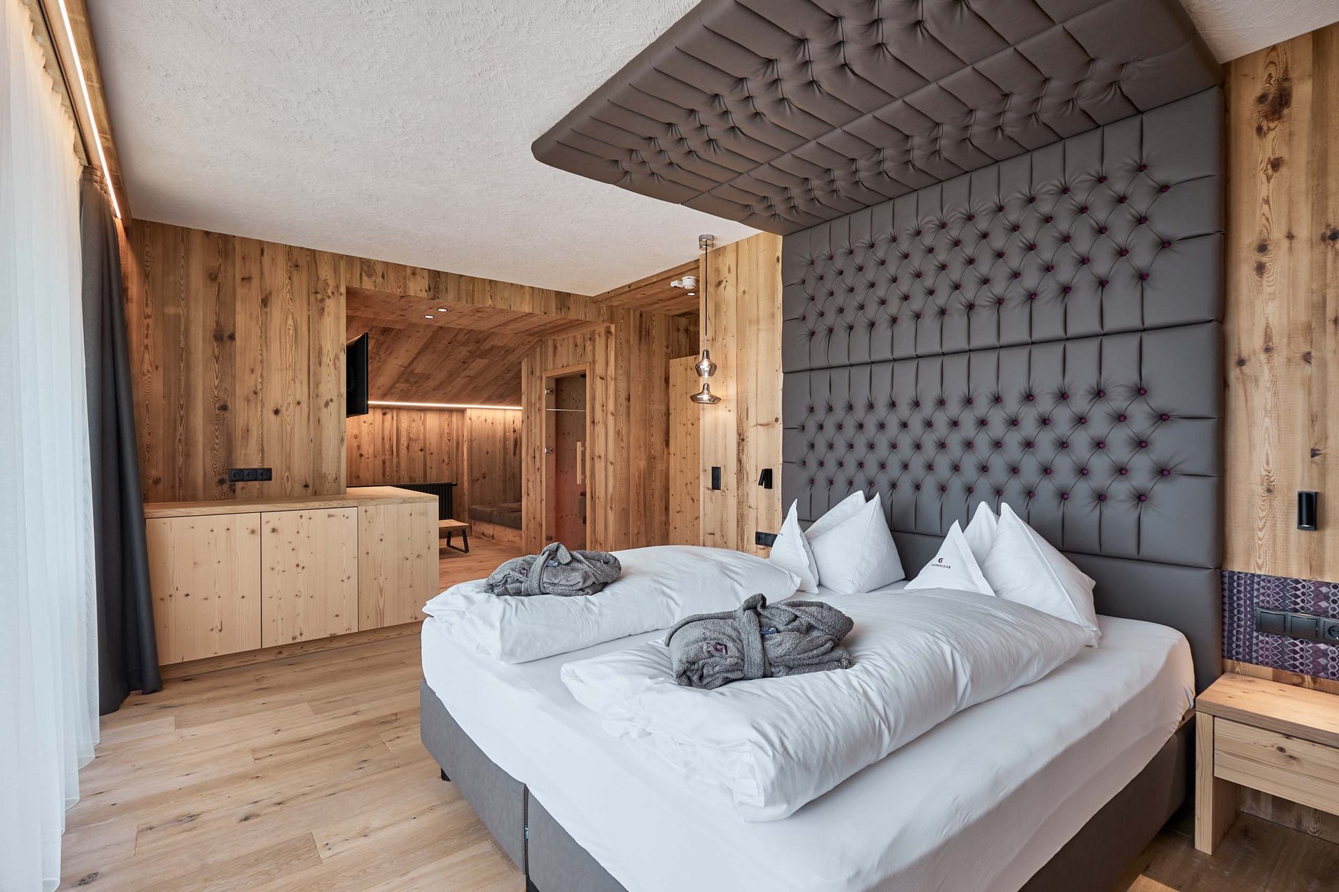Home Erlebnisort Gassenhof Moderne Holzzimmer mit großem Bett und grauem gepolstertem Kopfteil