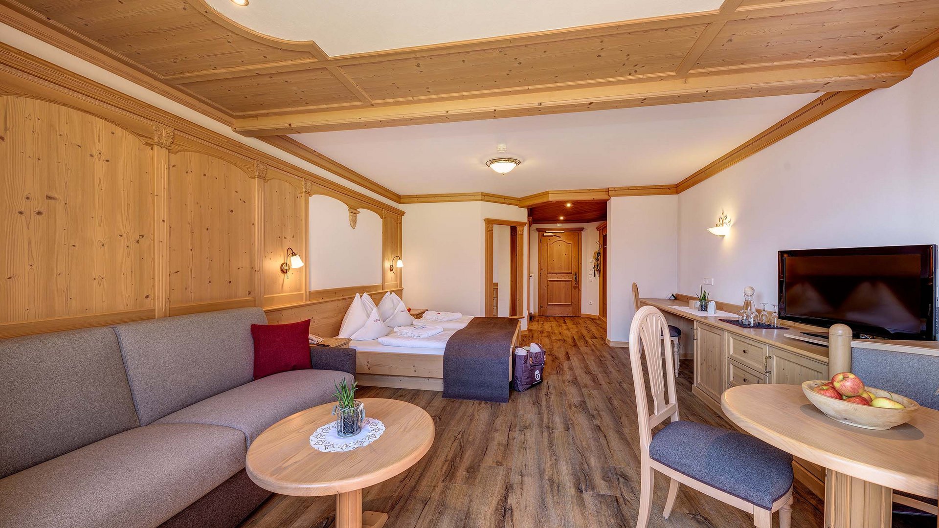 Home Erlebnisort Gassenhof Gemütliches Hotelzimmer mit Holzmöbeln, Couch, Bett, TV und Esstisch