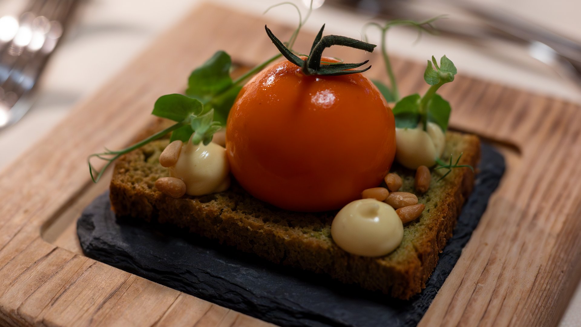 Gourmet haven Erlebnisort Gassenhof Pea bread with tomato, mayonnaise, pine nuts, and herbs on slate plate