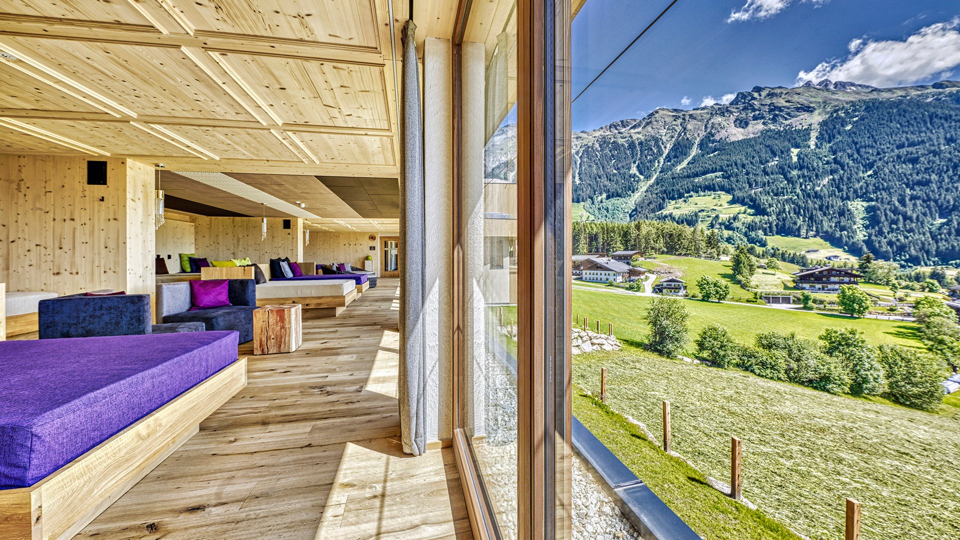 Home Erlebnisort Gassenhof Moderne Holzlounge mit lila Sitzen und Bergblick durch großes Fenster