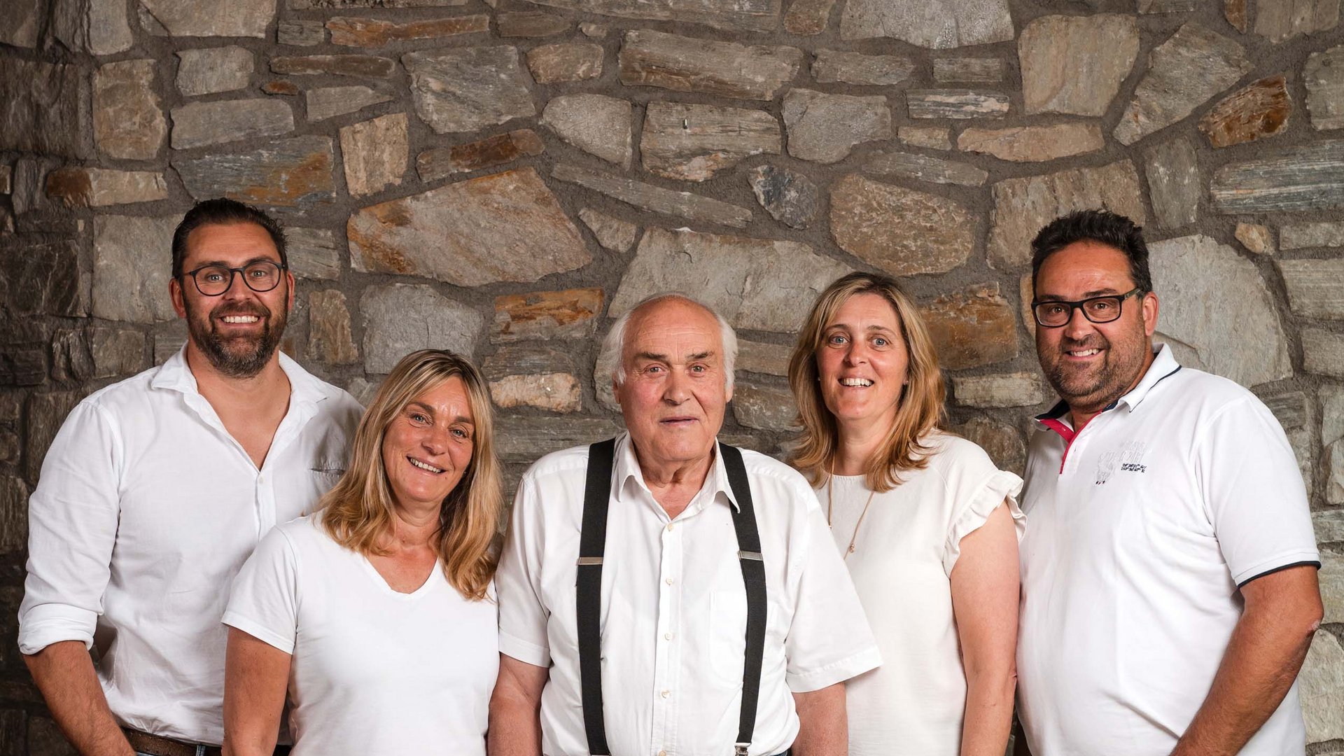 The Volgger family Five people smiling standing in front of a stone wall