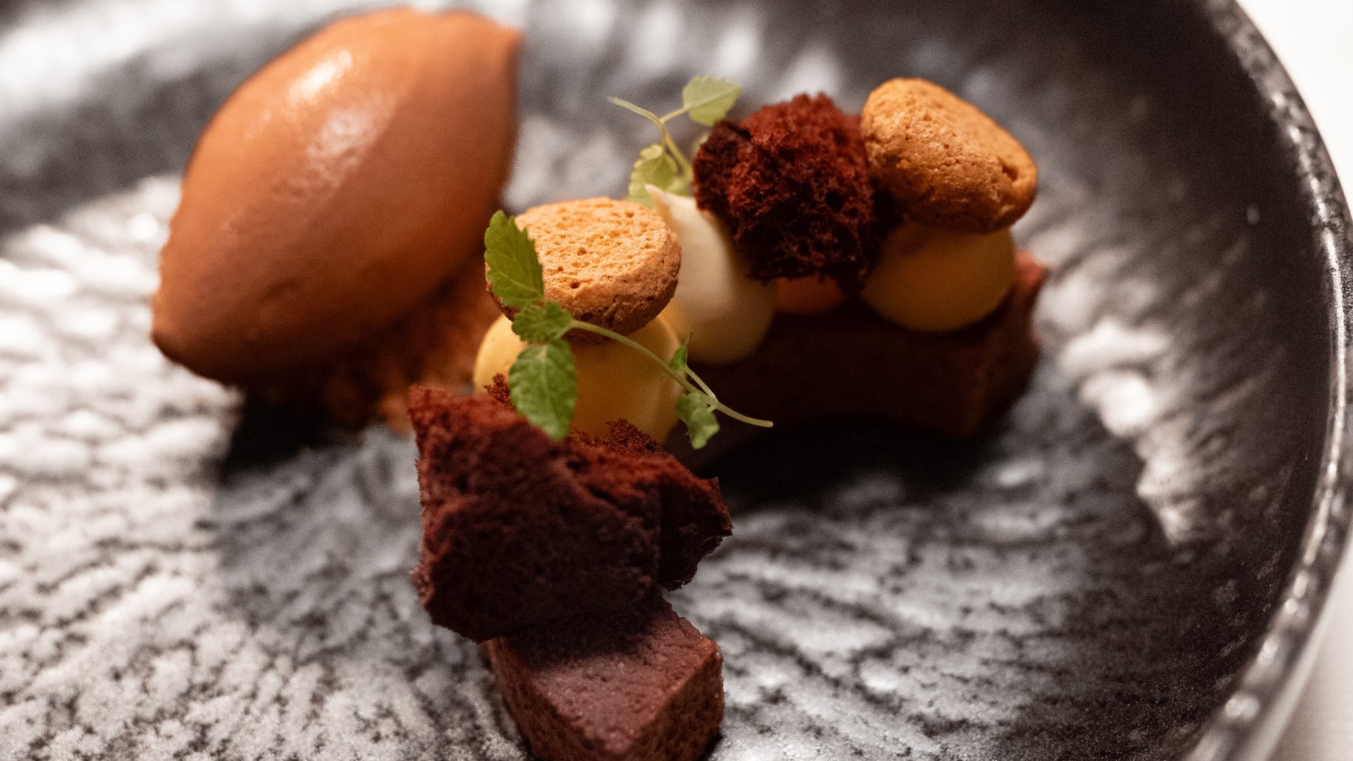 Gourmet haven Erlebnisort Gassenhof Artistic dessert with chocolate ice cream and small cake pieces on black plate