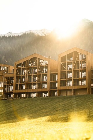 Home Erlebnisort Gassenhof Modernes Holzgebäude vor bewaldeten Bergen im Sonnenlicht