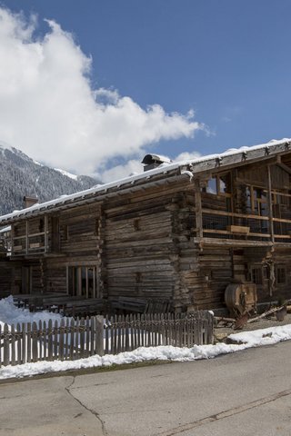 Home Erlebnisort Gassenhof Holzhaus mit Schnee im Winter vor Bergkulisse bei klarem Himmel